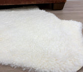 Natural white shearling rug styled on the floor showing short, tightly curled wool texture
