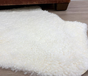 Natural white shearling rug styled on the floor showing short, tightly curled wool texture