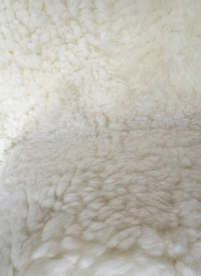Detailed view of genuine natural white shearling with dense wool and a soft, plush texture.