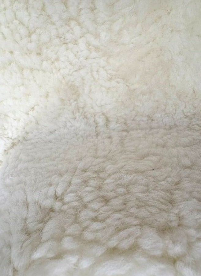 Detailed view of genuine natural white shearling with dense wool and a soft, plush texture.