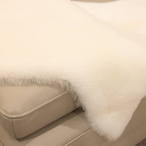 Close-up of natural white sheepskin baby rug showing dense wool pile and softly finished edge