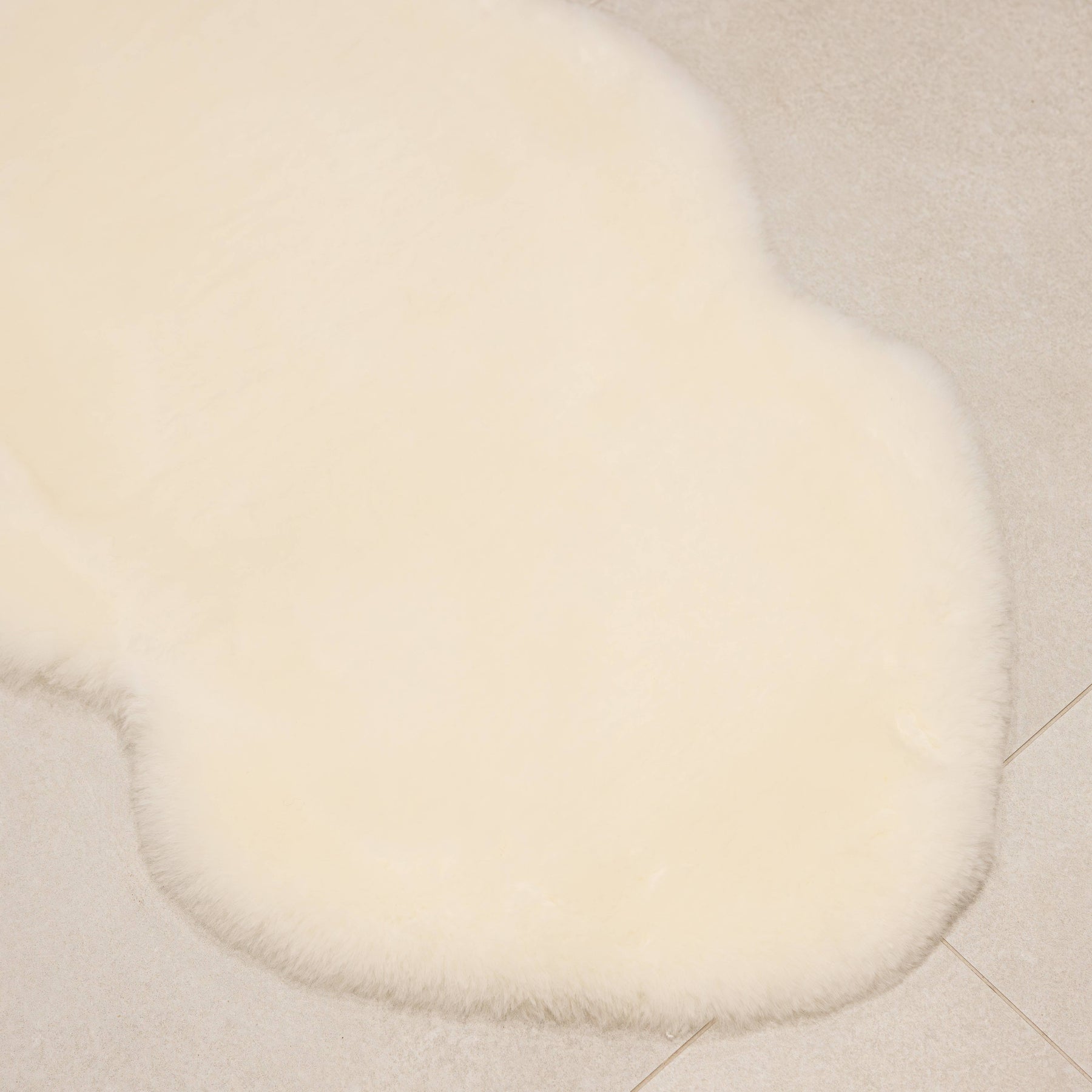 Natural white sheepskin baby rug laid flat showing natural shape and dense wool texture