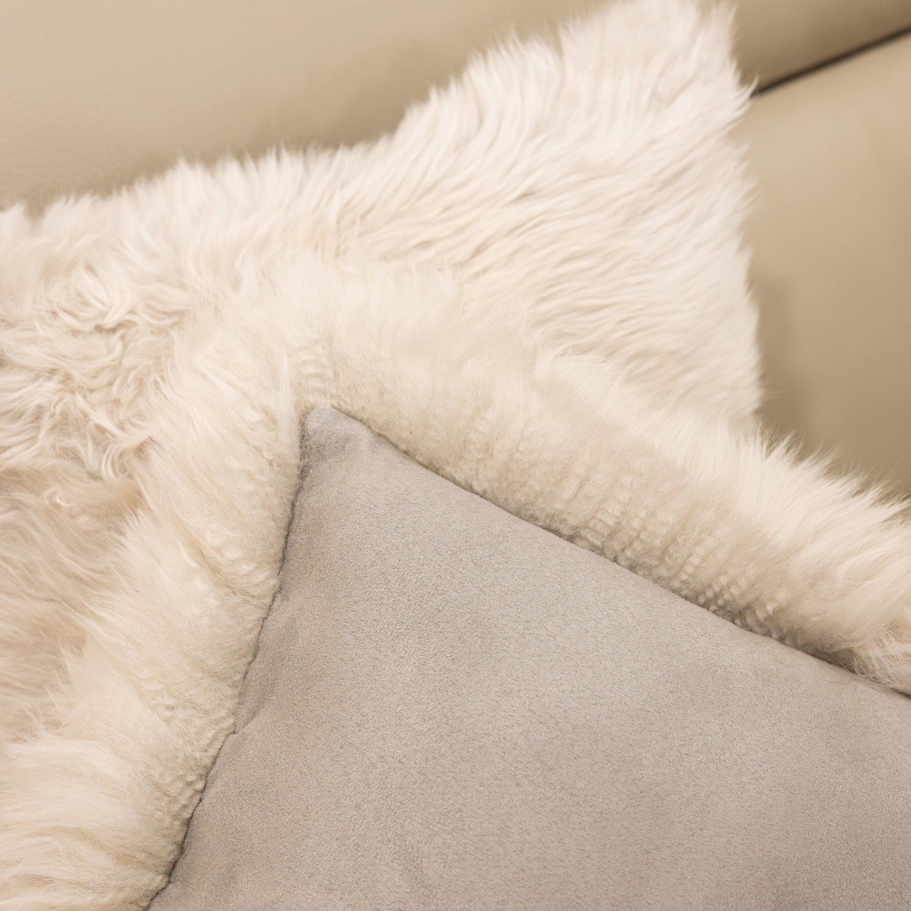 Close-up of New Zealand sheepskin cushion in linen showing soft long wool front and fabric backing detail