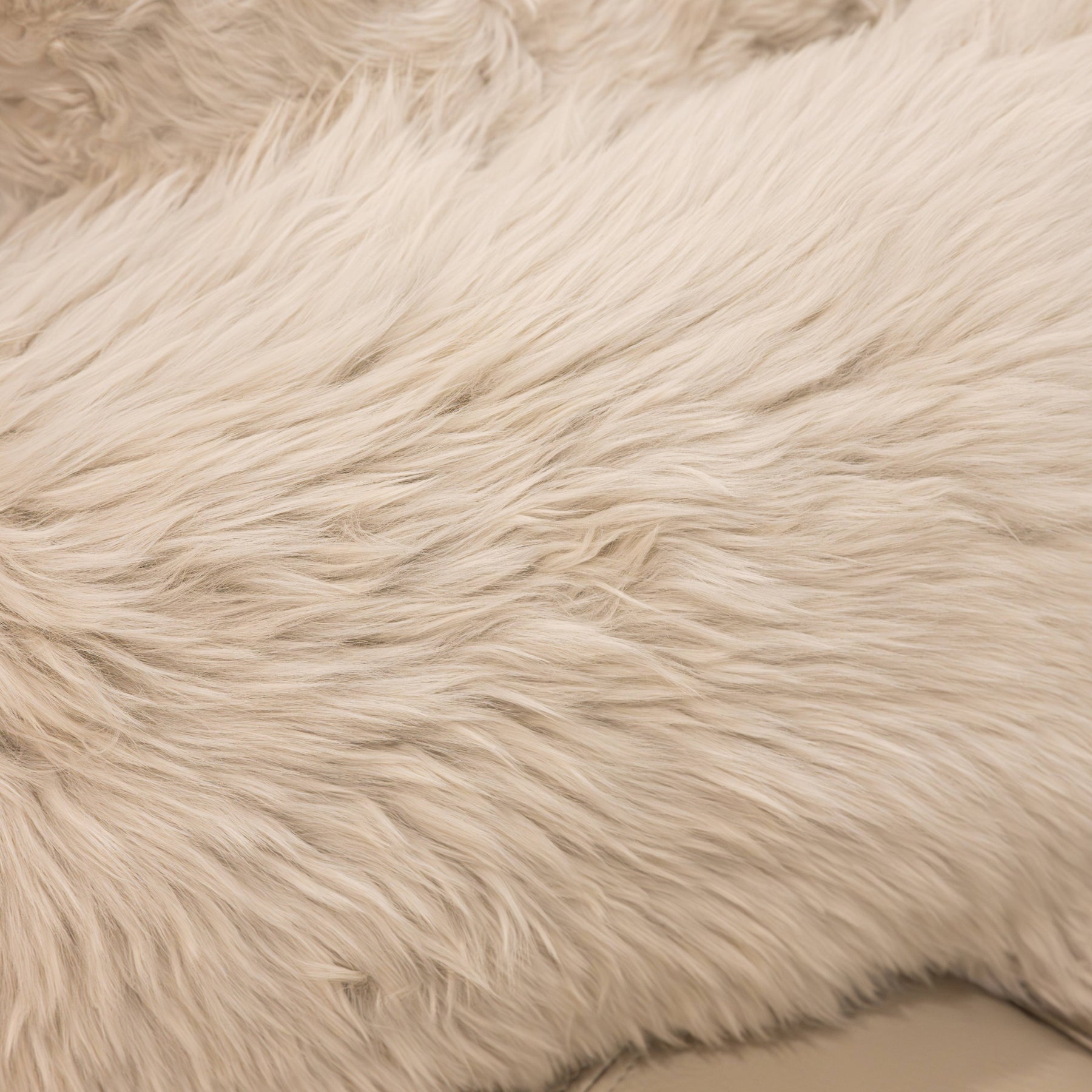 Close-up texture of New Zealand sheepskin cushion in linen showing soft long wool fibres and natural variation