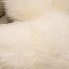Close-up of New Zealand sheepskin cushion in natural white showing soft long wool texture and natural fibre detail