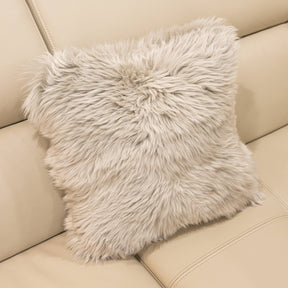 New Zealand sheepskin cushion in pale grey with plush long wool texture on a beige sofa