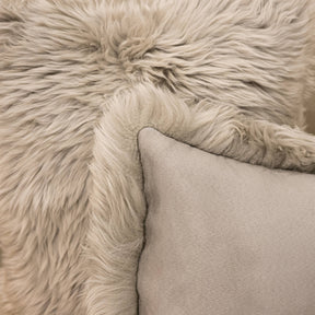 Close-up of New Zealand sheepskin cushion in pale grey showing soft long wool texture and backing detail