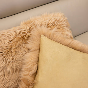 Close-up of New Zealand sheepskin cushion in sand showing plush long wool front and soft backing fabric detail