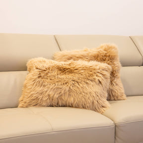 Two New Zealand sheepskin lumbar cushions in sand styled together on a beige sofa