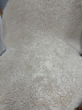 Close-up of oatmeal shearling rug showing soft, tightly curled wool texture.