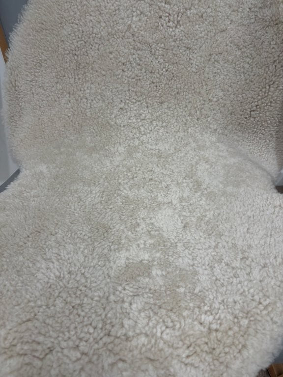 Close-up of oatmeal shearling rug showing soft, tightly curled wool texture.