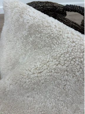Close-up of oatmeal shearling rug featuring dense, tightly curled wool and a soft texture.