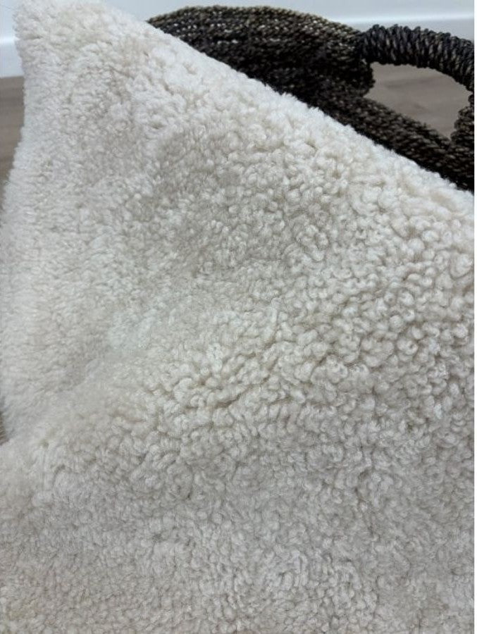 Close-up of oatmeal shearling rug featuring dense, tightly curled wool and a soft texture.