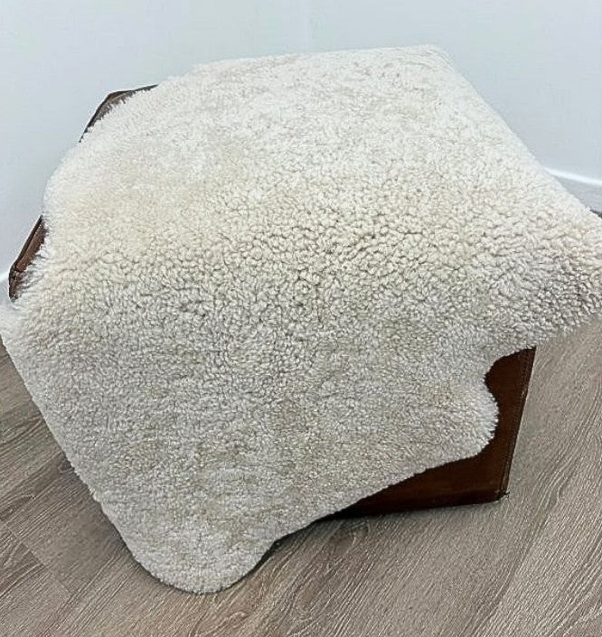 Oatmeal shearling rug draped over furniture, highlighting soft curly wool and natural texture.