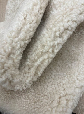 Detailed view of genuine oatmeal shearling with dense, curly wool and a luxurious soft finish.