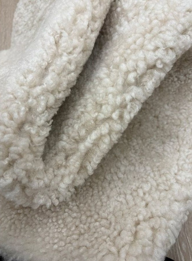 Detailed view of genuine oatmeal shearling with dense, curly wool and a luxurious soft finish.