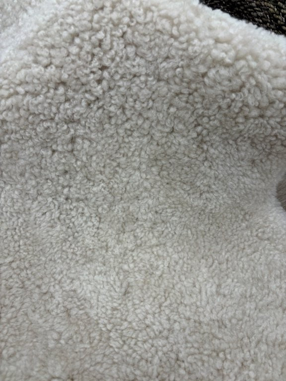 Detailed view of oatmeal shearling sheepskin with a dense, tightly curled wool surface.