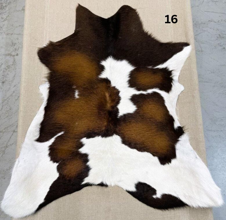 Reddish brown calf hide rug number 16 with natural markings and central white pattern on a neutral background