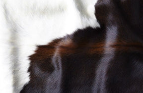 Close-up detail of a large reddish brown cowhide rug showing smooth natural hair texture and colour variation