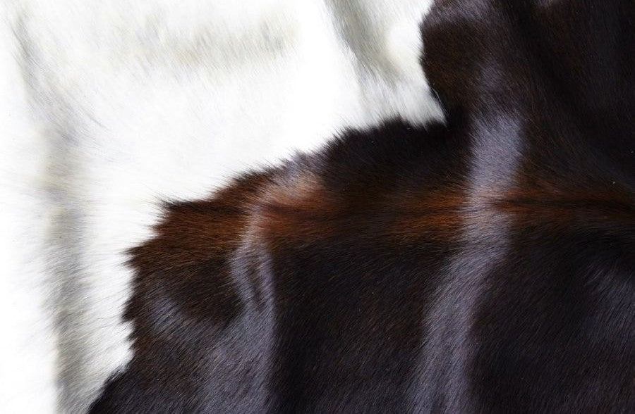Close-up detail of a large reddish brown cowhide rug showing smooth natural hair texture and colour variation