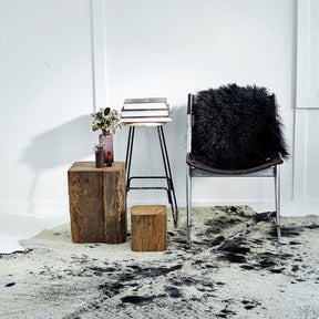 Natural salt and pepper cowhide rug styled in a modern interior with accent chair and side table