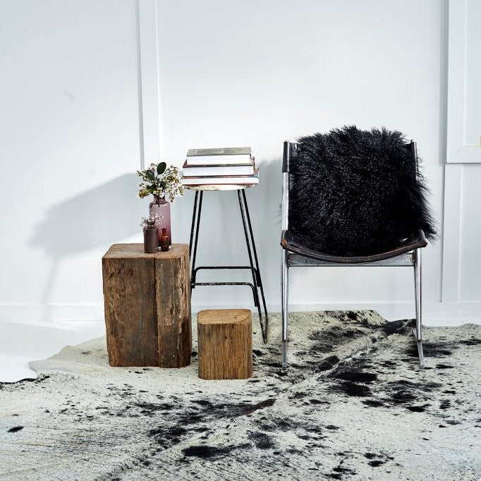 Natural salt and pepper cowhide rug styled in a modern interior with accent chair and side table