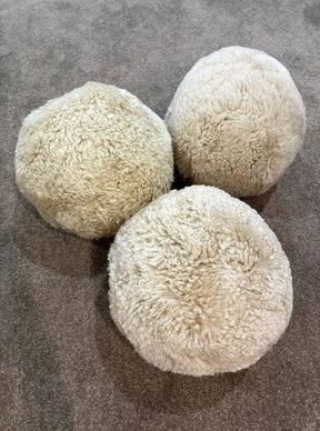 Three shearling accent balls in bone colour grouped together, showcasing their round sculptural form and soft textured shearling surface
