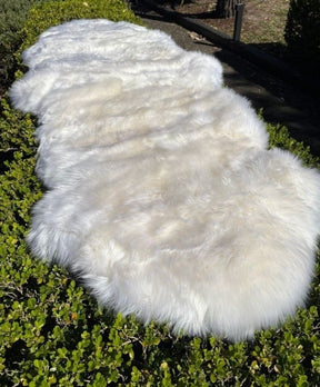 White Merino sheepskin double hide made from two skins sewn together, photographed outdoors on grass in natural light