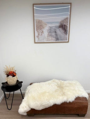 White Merino sheepskin double hide made from two skins sewn together, styled on a bench in a neutral interior