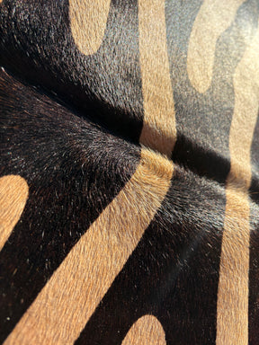 Zebra print cowhide rug texture showing black pattern and natural beige hide with visible hair-on-hide grain