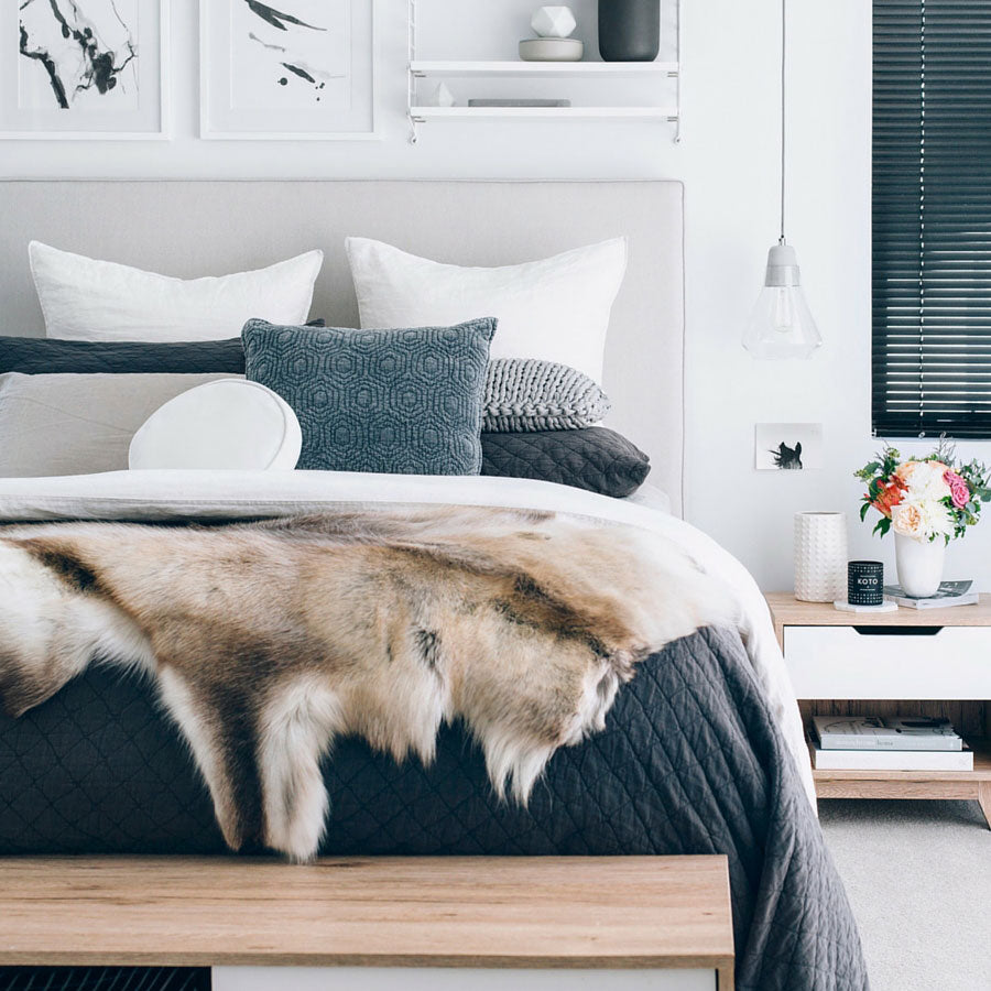 Beige reindeer hide throw styled across a bed showing natural hair texture and markings