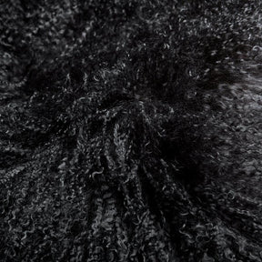Close-up detail of black Mongolian sheepskin cushion showing long, soft hair texture