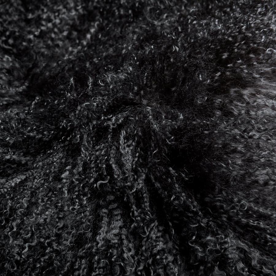 Close-up detail of black Mongolian sheepskin cushion showing long, soft hair texture