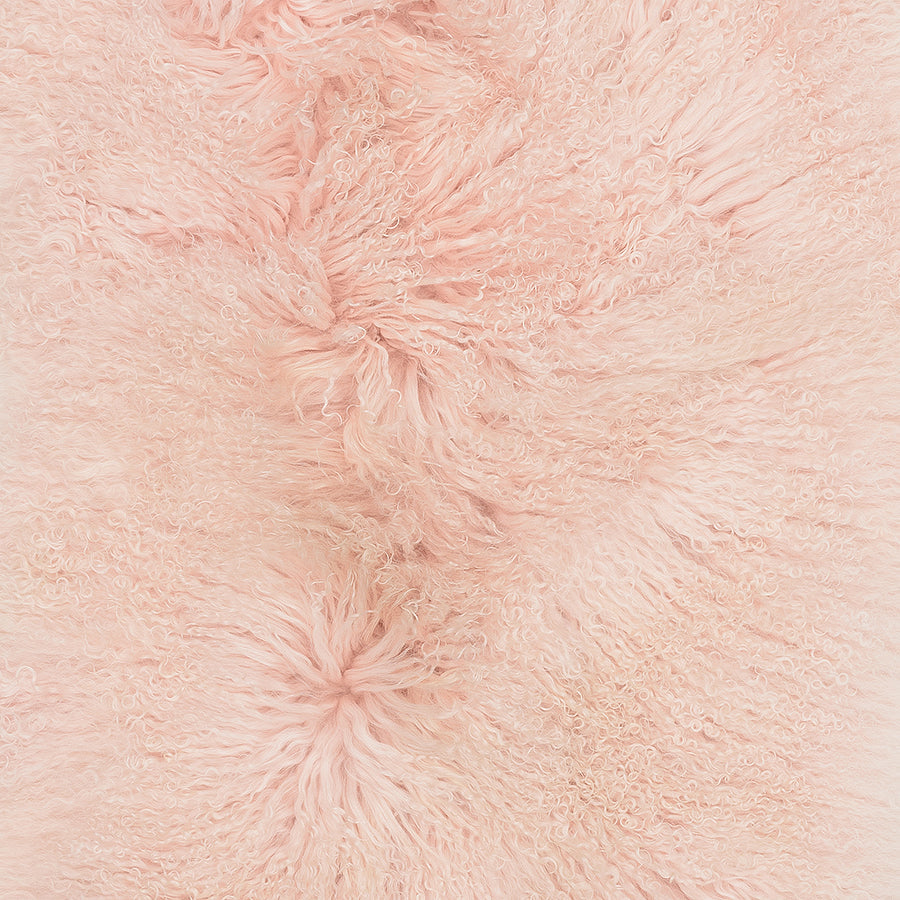 Close-up detail of blush Mongolian sheepskin cushion showing long, soft hair texture