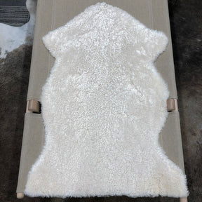 Bone shearling rug laid flat showing natural hide shape and short, tightly curled wool texture