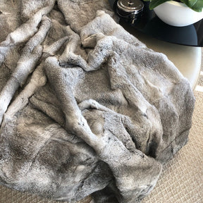 Grey rabbit hide blanket draped over a chair showing natural soft hair texture