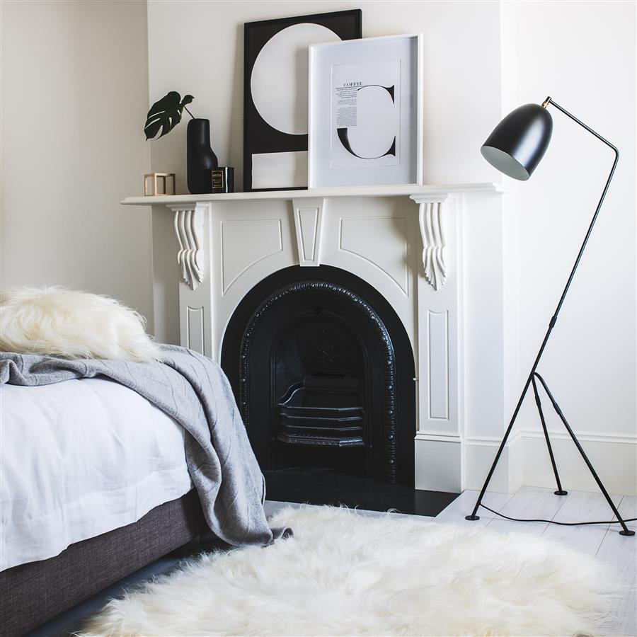 Icelandic sheepskin floor rug in natural white made from three hides stitched together, styled in a bedroom beside a fireplace