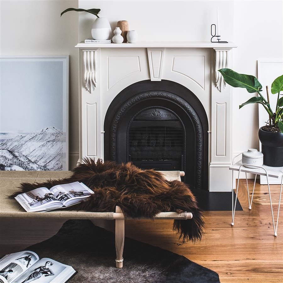 Icelandic sheepskin rug in brown with auburn tips styled on a bench in a living room setting