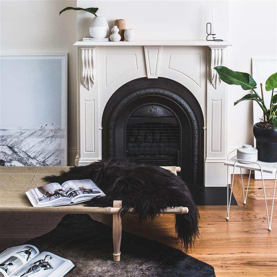 Brown and black Icelandic sheepskin rug styled on a bench in front of a fireplace