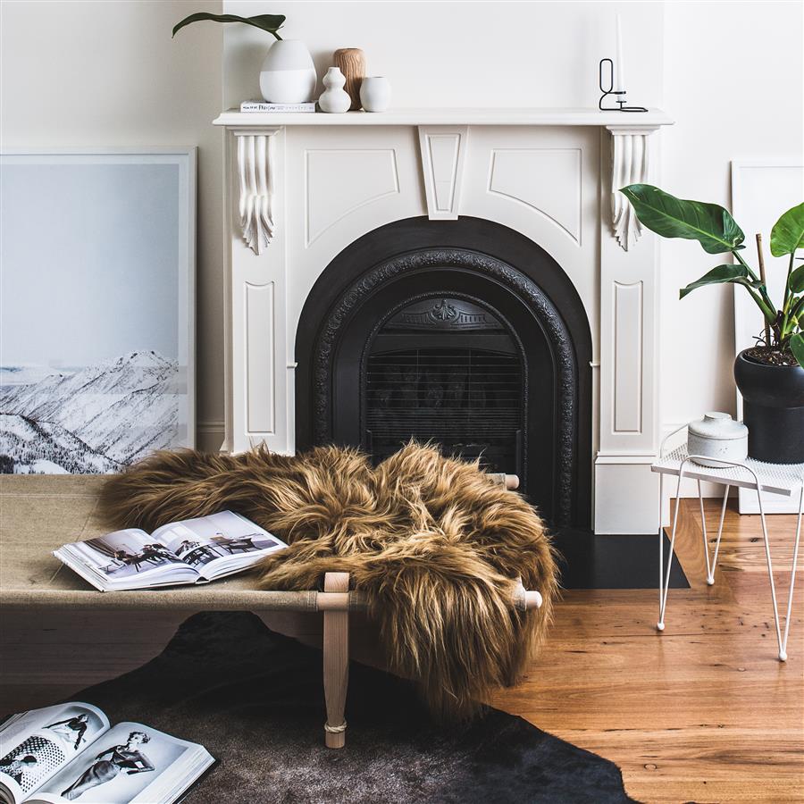 Icelandic sheepskin rug in copper with caramel tips styled over a bench in a living room