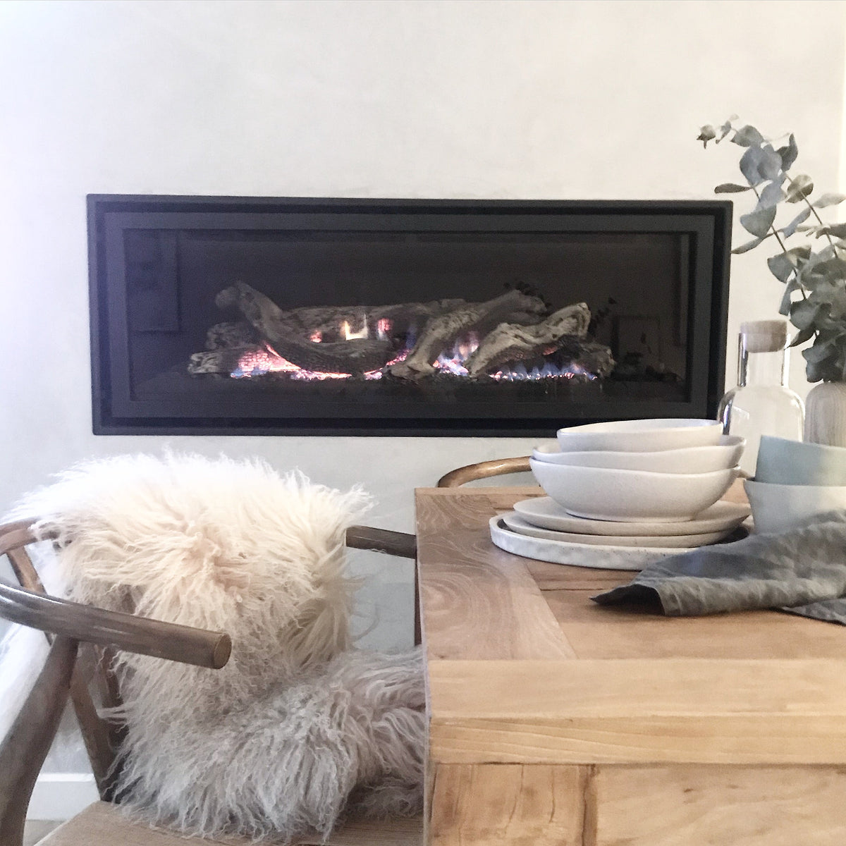 Fawn Mongolian sheepskin rug styled over a wooden chair beside a fireplace