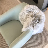 Grey Mongolian sheepskin rug with white tips styled over a modern armchair