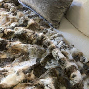 White and brown rabbit hide blanket draped across a sofa showing natural hair texture and colour variation