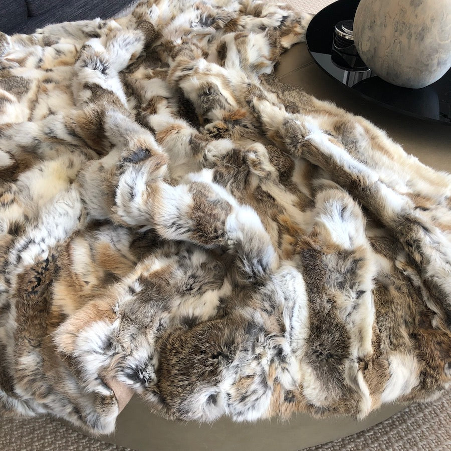 White and brown rabbit hide blanket spread across a surface showing naturally soft hair texture