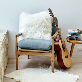 White Mongolian sheepskin cushion with long hair texture styled on a timber chair in a relaxed living space