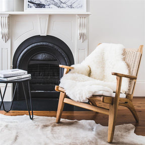 Icelandic shorn sheepskin rug in natural white styled over an armchair in a living room setting