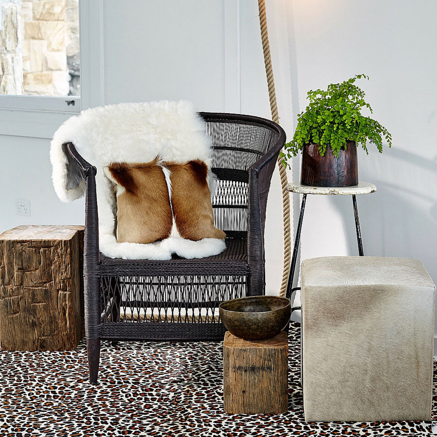 Icelandic shorn sheepskin rug in natural white styled over a woven chair in a contemporary interior setting